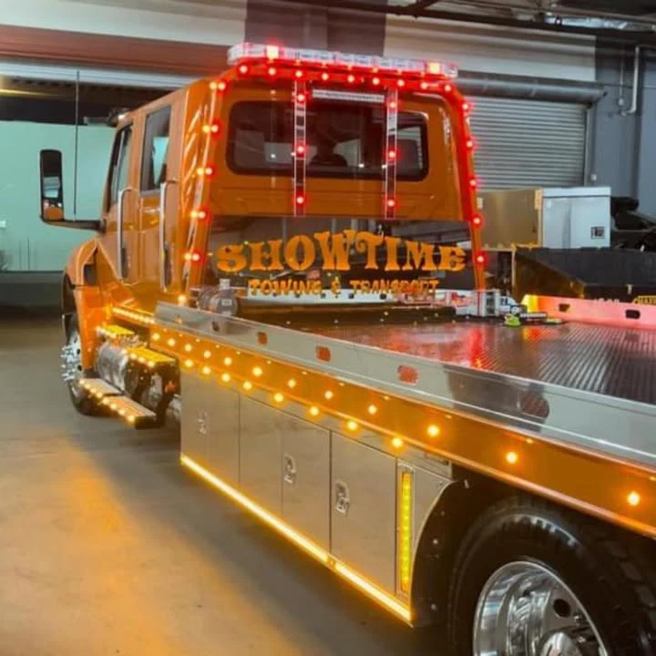 Showtime Towing's orange International flatbed, lit up in the shop